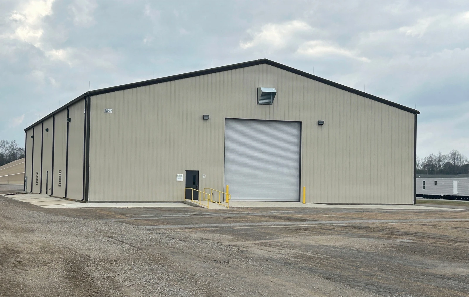 Reference photograph of an enclosed metal warehouse with ribbed wall panels and a large overhead door
